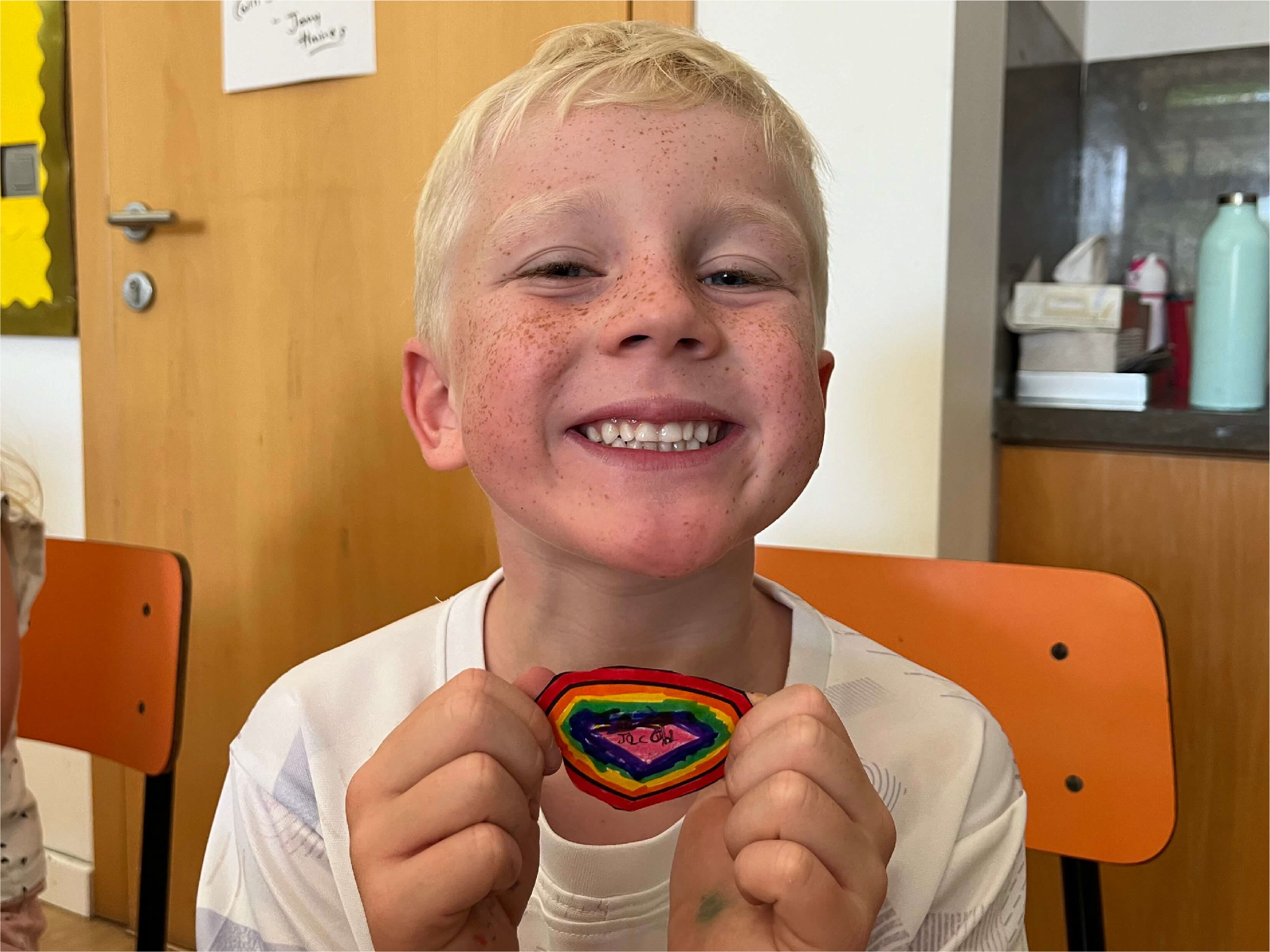 A boy smiling with his finished shield for the wall display