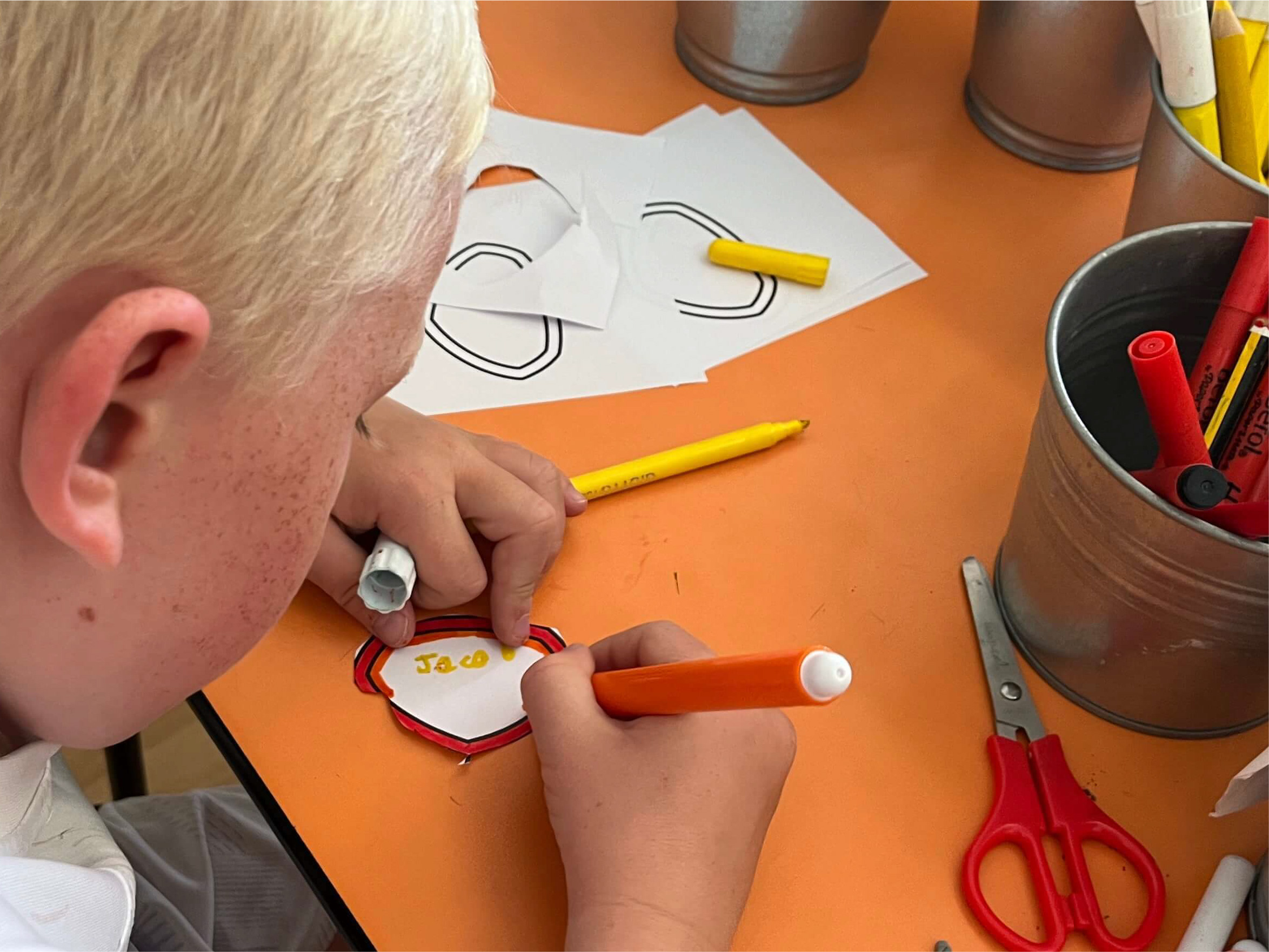 A boy colouring his shield for the wall display