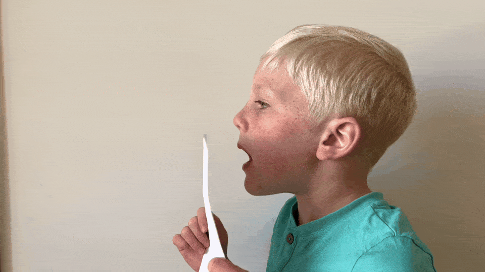 A boy facing sideways talking into a piece of paper