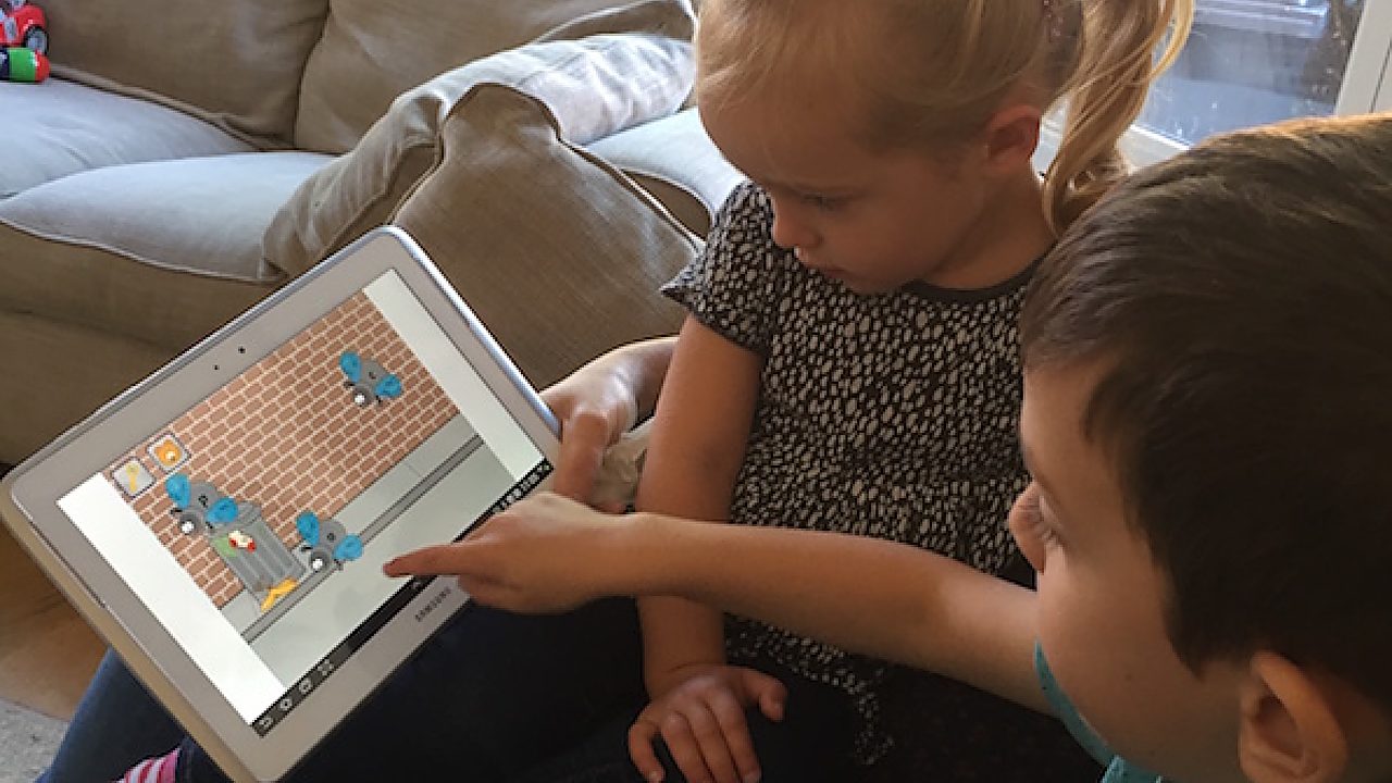 Two children playing a Phonics Hero game on a tablet at home